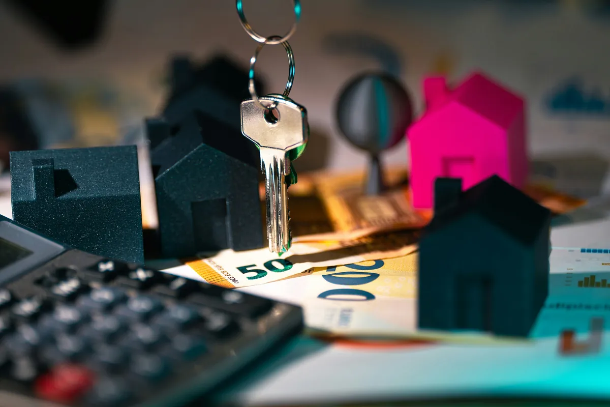 Calculator, house model and key on a table