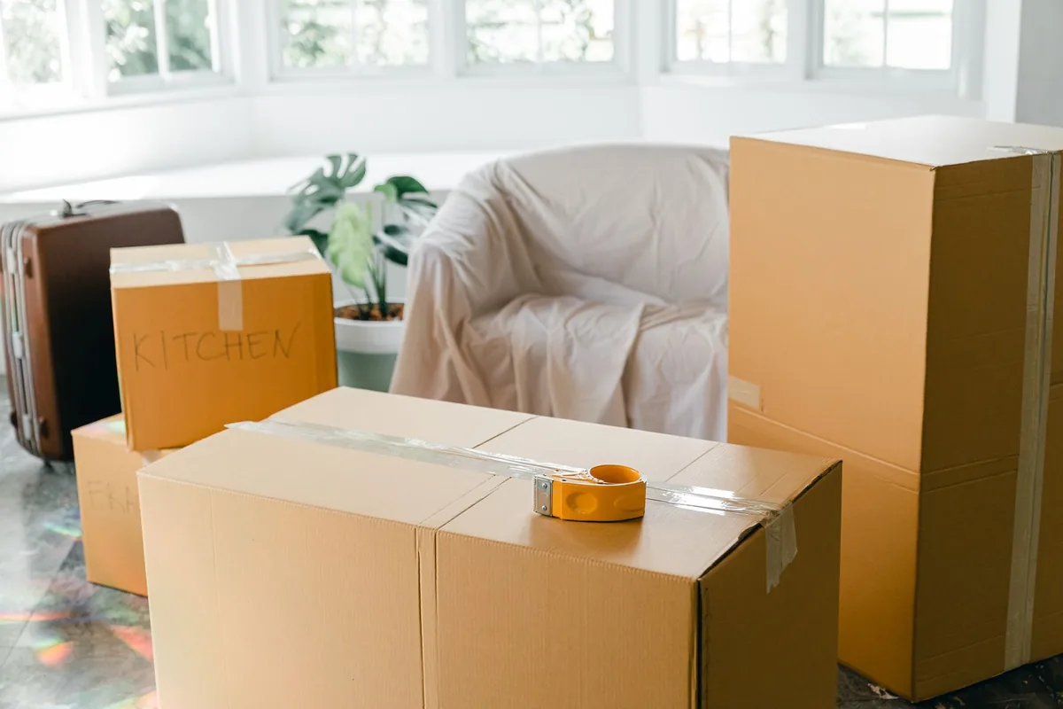 Navid Hakimi Group Downsizing in North Vancouver and West Vancouver: From House to Condo or Townhome 3 Packed moving boxes in a bright living room