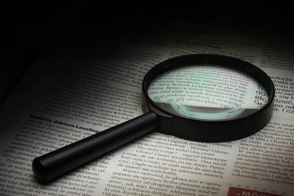 Magnifying glass over printed text, reviewing the details