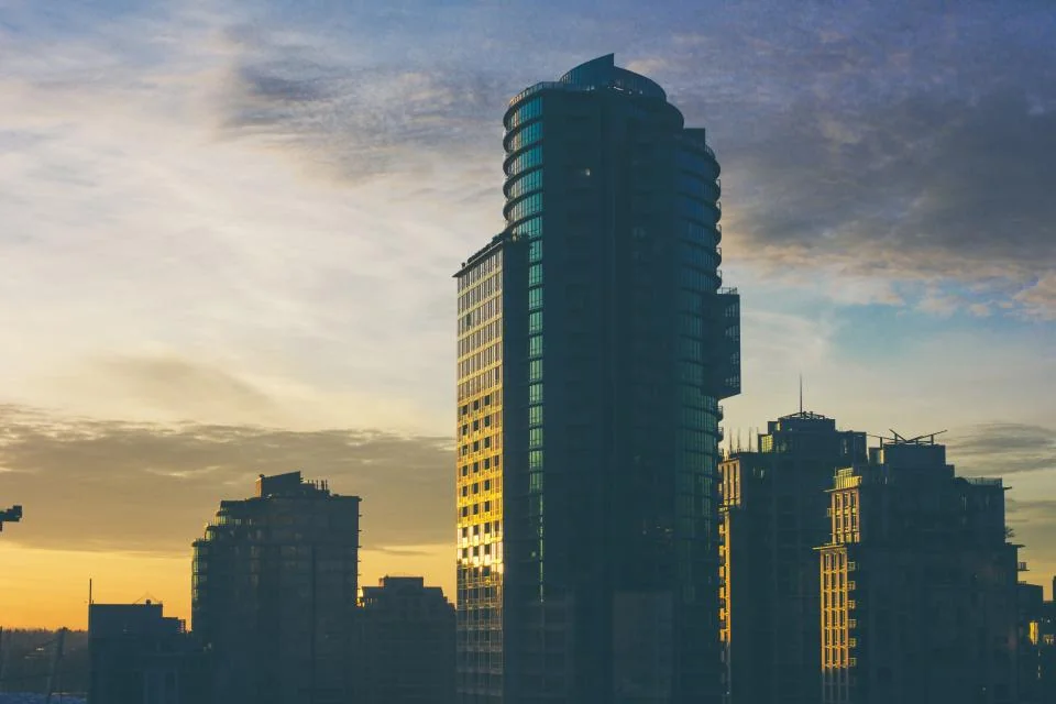 Navid Hakimi Group Best Presale Condos in North Vancouver (2026 to 2029 Completions) 2 Glass condo tower silhouetted against the evening sky
