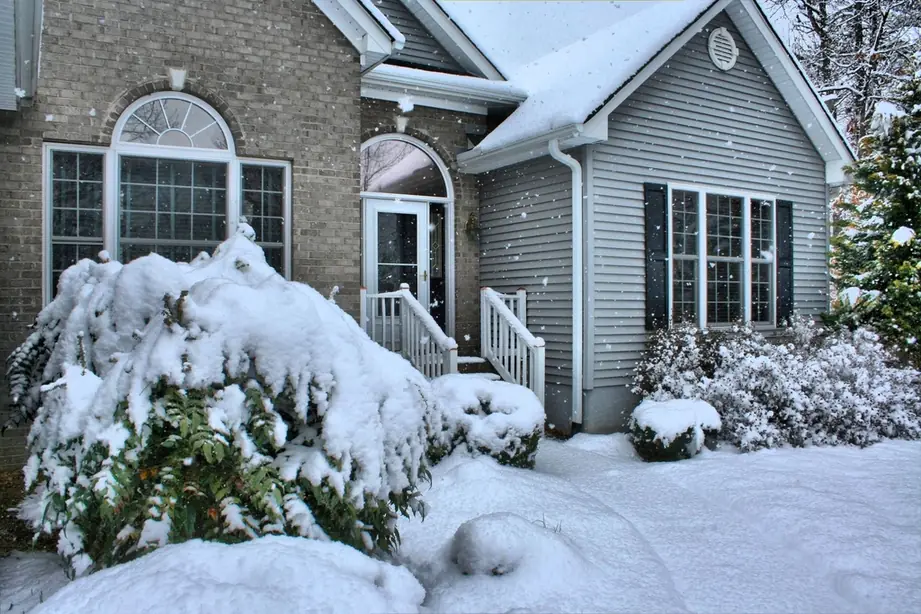 Two-storey family home with snow-covered shrubs in winter