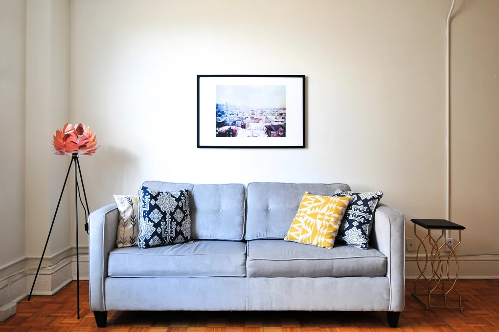 Navid Hakimi Group Why Is My House Not Selling? 9 Reasons and How to Fix Them 2 Simple, uncluttered living room with a sofa and framed art