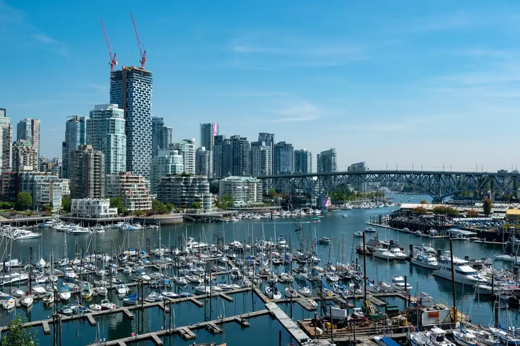 Vancouver condo towers and construction cranes above a waterfront marina